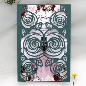 Detail of dark green laser-cut wedding invitation with elegant rose pattern
