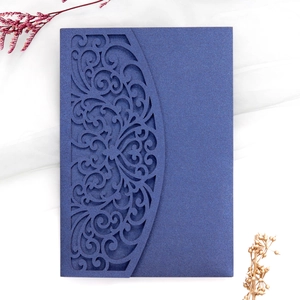 Detail view of laser-cut floral pattern on navy blue pearlescent paper invitation