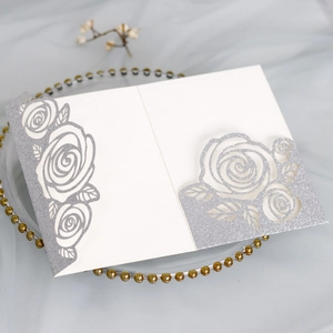 Macro detail of laser-cut rose patterns on silver glitter wedding invitation cards