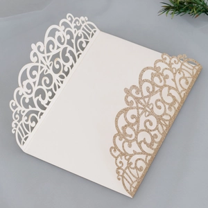 Detail of laser-cut hollow lace invitation with elegant gold glitter coating on cream paper