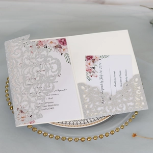 Detailed laser-cut silver glitter wedding invitation with floral insert and RSVP card set