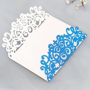 Detail of laser-cut wedding invitation featuring blue glitter and white lace patterns