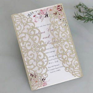 Close-up of laser-cut gold glitter invitation with floral inner card detail
