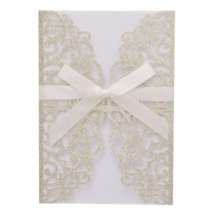 Detailed laser-cut champagne gold glitter invitation cover with a white ribbon bow