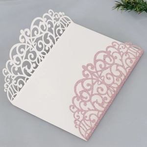 Detail of laser-cut glitter wedding invitation with elegant hollow patterns and pink finish