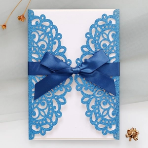 Detail of blue glitter laser-cut invitation with navy ribbon and premium white insert