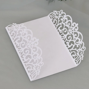 Detailed laser-cut floral patterns on white wedding invitation covers from a 45-degree angle