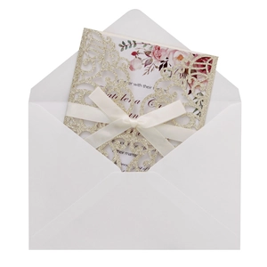 Detail of glitter laser cut wedding invitation with silk bow and floral insert card