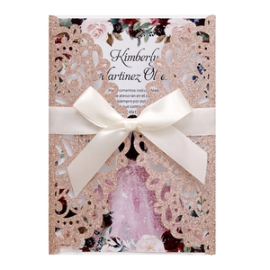 Detail of rose gold glitter laser-cut invitation with white satin bow and floral insert