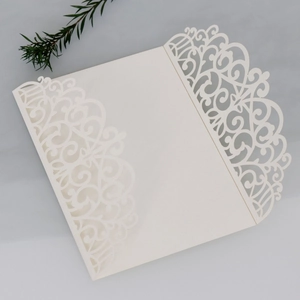 Detail of white laser-cut invitation card with elegant floral vines and three-fold design