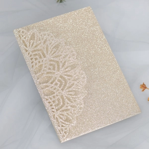 Detail of glitter gold wedding invitation with intricate laser-cut lace floral pattern