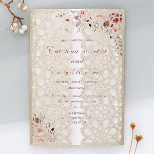 Detail of laser-cut gold glitter invitation with elegant watercolor floral insert card