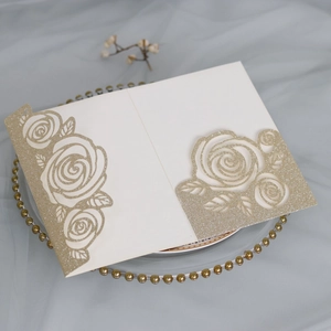 Detail of laser-cut rose patterns with gold glitter finish on ivory paper card