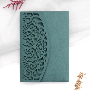 Detailed laser-cut dark green wedding invitation on white gauze with dried flowers