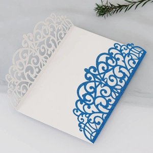 Close-up of laser-cut floral pattern and blue glitter finish on white paper invitation