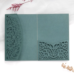 Detail of dark green laser-cut wedding invitation with intricate floral lace patterns