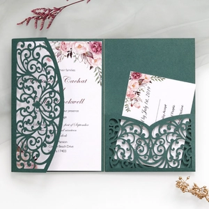 Dark green laser cut wedding invitation with intricate scroll pattern and floral inner card