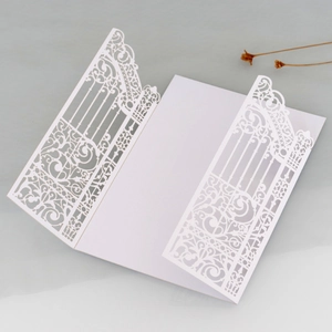 Detail of laser cut white wedding invitation with elegant baroque iron gate pattern