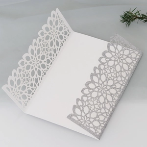 Close-up of laser-cut wedding invitation with silver glitter floral pattern