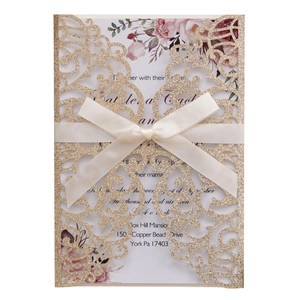 Detail of laser-cut glitter wedding invitation with silk bow and floral interior card