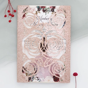 Detail of rose gold laser-cut floral wedding invitation with pink glitter finish