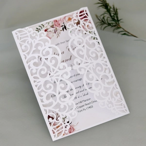 Detail showing laser-cut white wedding invitation with elegant pink floral printed insert