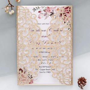 Macro detail of laser-cut champagne gold glitter scrollwork on wedding invitation cover