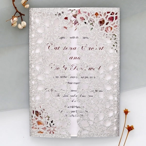 Detailed laser-cut floral pattern on silver glitter wedding invitation with inner card