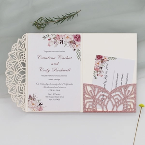 Close-up of laser-cut glitter wedding invitation with floral insert and RSVP card