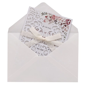 Detail of laser-cut wedding invitation with pink floral inner card and silk ribbon bow