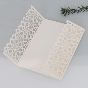 Macro detail of laser-cut ivory wedding invitation with glitter finish and floral pattern