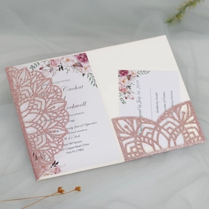 Macro detail of laser-cut rose gold glitter wedding invitation with floral insert card