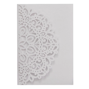 Close-up of white laser-cut invitation with intricate mandala floral patterns on paper