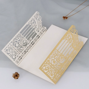 Detail of laser-cut European wedding invitations with elegant white and gold floral patterns