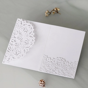Detail of laser-cut white wedding invitation featuring intricate mandala floral patterns