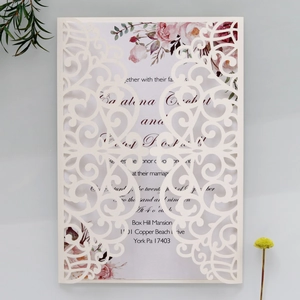 Intricate laser-cut cream wedding invitation with floral inner card and botanical decor