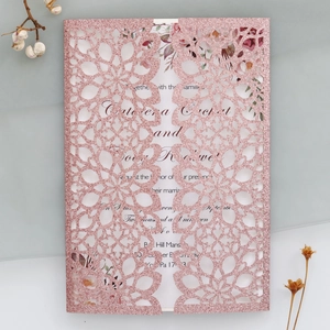 Detailed view of laser-cut glitter paper wedding invitation with floral inner card