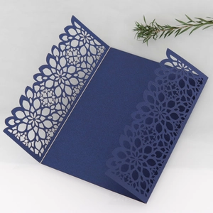 Dark blue laser cut wedding invitation covers with intricate floral pattern on paper