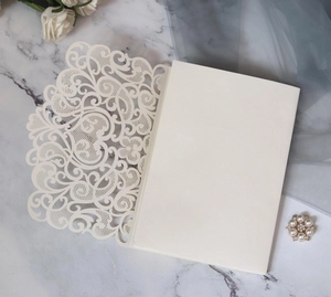 Detailed laser-cut ivory wedding invitation featuring intricate floral patterns and heart motif