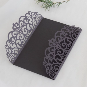 Detail of laser-cut black wedding invitation cover with elegant European scroll patterns