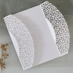 Detail of laser-cut lace pattern on pearl white wedding invitation card cover