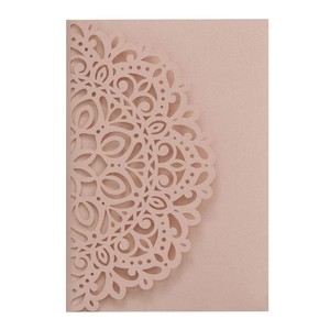Macro view of laser-cut mandala pattern on elegant pearlescent pink invitation paper