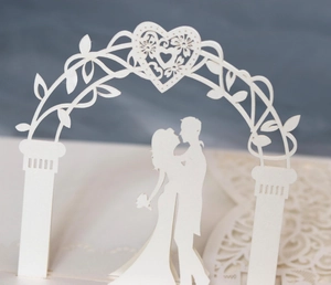 Macro view of laser-cut 3D greeting card featuring a couple silhouette and floral heart arch