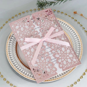 Laser-cut pink glitter wedding invitation with silk bow on decorative gold rim plate