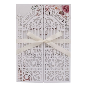 Detailed laser-cut wedding invitation featuring white lace cover and cream satin ribbon