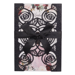 Detailed laser cut black glitter invitation with floral insert and black ribbon bow