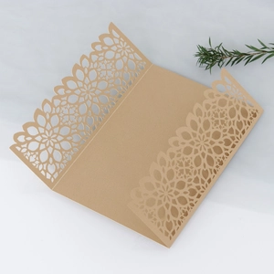 Detailed laser-cut champagne gold wedding invitation with intricate floral lace patterns