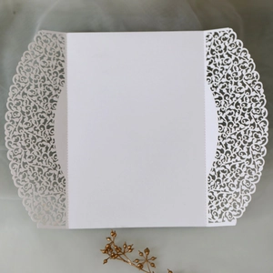 Detail of laser-cut floral pattern and vine texture on elegant white wedding card