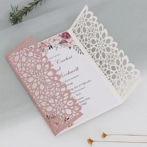 Detail of laser-cut glitter wedding invitation with floral card and delicate hollow patterns