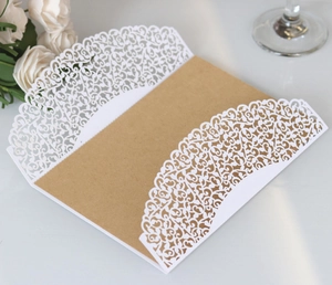 Macro shot of white laser-cut floral lace wedding invitation with kraft paper insert